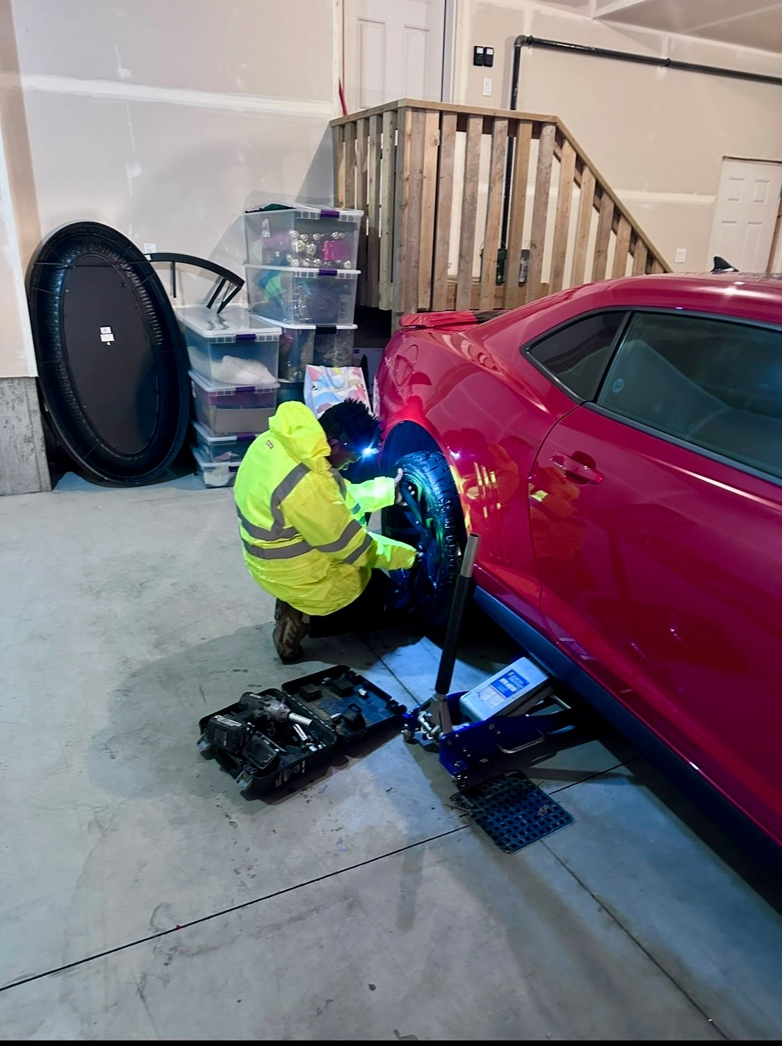 Mobile tire change on a red sports car in Edmonton garage