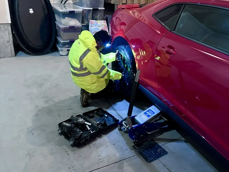 Mobile tire change on a red sports car in Edmonton garage